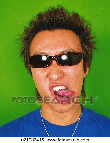 Stock Photography - Young Man Making a Face, Wearing Sunglasses, Portrait, Front View. Fotosearch