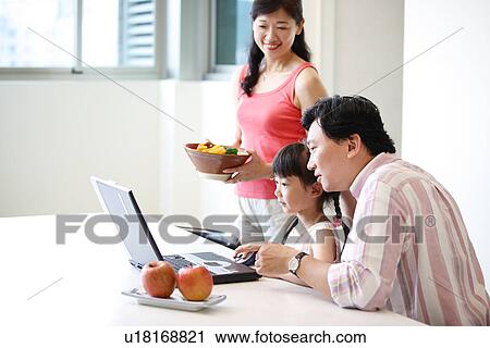 Stock Image - A daughter learning on laptop with her father.. Fotosearch