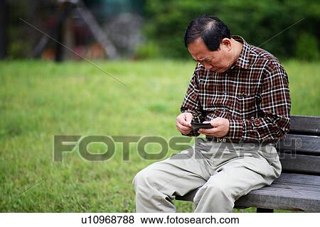 Stock Photo - A man sitting in a garden on bench.. Fotosearch