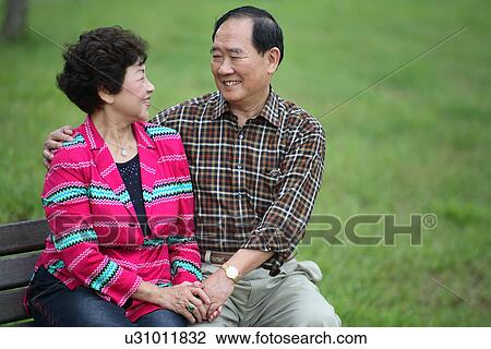 View of a couple sitting in a garden. View Large Photo Image Stock Image - View of a couple sitting in a garden.. Fotosearch