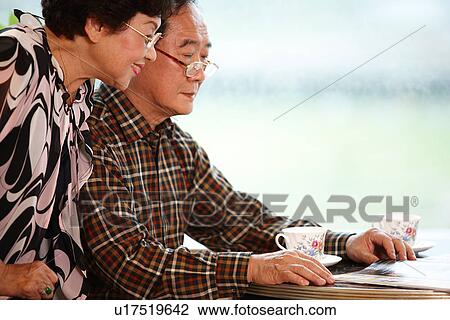 View of a couple sitting reading paper. View Large Photo Image Stock Image - View of a couple sitting reading paper.. Fotosearch