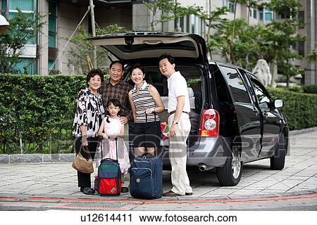 Stock Image - View of a family standing beside a car.. Fotosearch