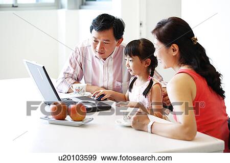 Stock Photo - View of a girl and her parent looking at the laptop.. Fotosearch