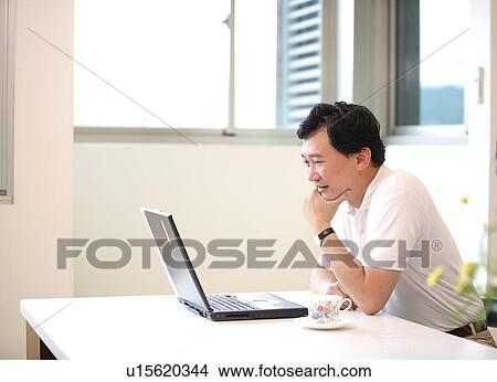 Picture - View of a man looking at laptop.. Fotosearch