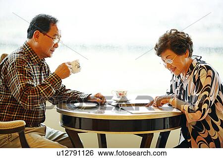 Stock Photograph - View of a senior couple on coffee table.. Fotosearch