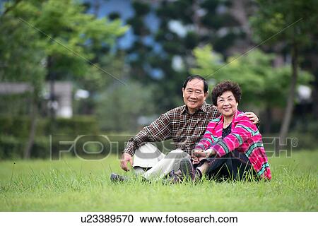Stock Image - View of aged couple relaxing at park.. Fotosearch