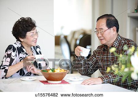 Stock Image - View of aged couple with cups in hand.. Fotosearch