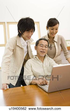 Stock Image - A Family Using a Laptop Computer Together, Front View, Side View. Fotosearch