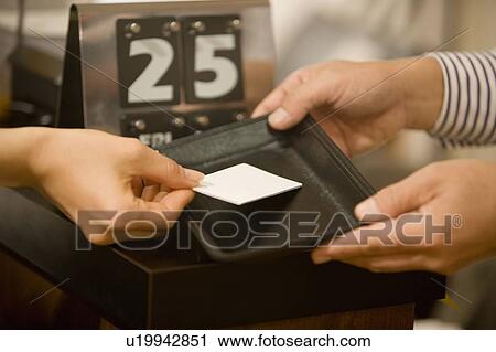 Stock Image - A Hand Placing a Credit Card on a Tray, Side View, Close Up, Differential Focus. Fotosearch