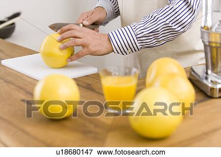 Stock Photo - A Man Making Grapefruit Juice, Side View, Differential Focus. Fotosearch