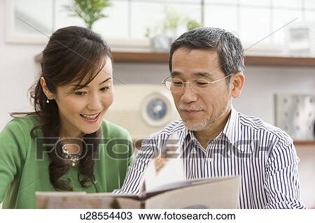 Stock Image - A Mature Adult Couple Reading a Book Together, Front View, Differential Focus. Fotosearch