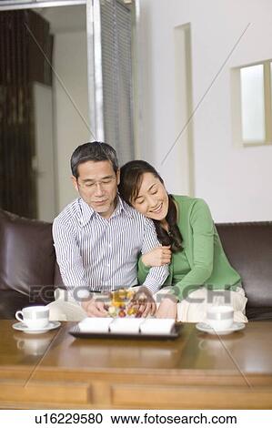 Stock Image - A Mature Adult Couple Relaxing on a Sofa, Front View, . Fotosearch