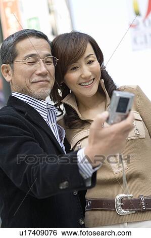 Stock Photograph - A Mature Adult Couple Taking a Picture of Themselves, Front View, Side View Differential Focus. Fotosearch