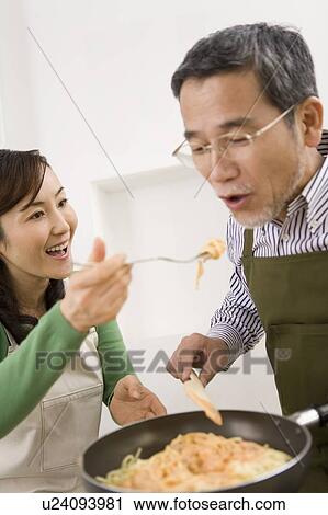 Stock Image - A Mature Adult Man Cooking and Tasting, Side View. Fotosearch