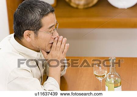Stock Photo - A Mature Adult Man Enjoying a Glass of Wine, Side View, High Angle View, Differential Focus. Fotosearch