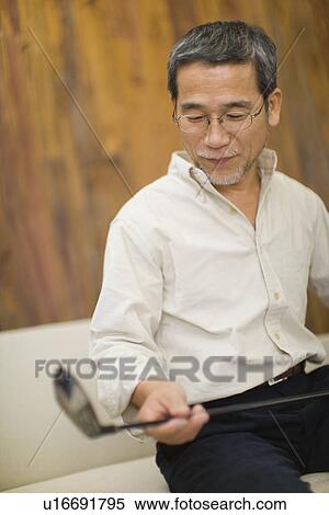 A Mature Adult Man Holding and Looking at a Golf Club, Side View, Differential Focus View Large Photo Image Stock Photography - A Mature Adult Man Holding and Looking at a Golf Club, Side View, Differential Focus. Fotosearch