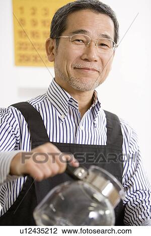 Stock Image - A Mature Adult Man Smiling and Pouring Coffee, Front View, Side View, Differential Focus. Fotosearch