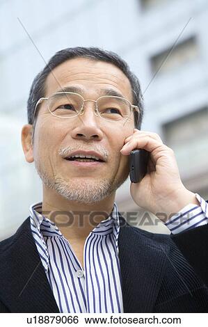 Stock Photograph - A Mature Adult Man Talking on a Mobile Phone, Low Angle View, Differential Focus, Close Up. Fotosearch