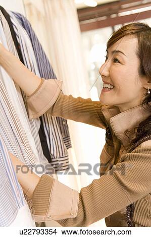 A Mature Adult Woman Choosing Clothes at a Clothes Shop, Side View, Differential Focus View Large Photo Image Picture - A Mature Adult Woman Choosing Clothes at a Clothes Shop, Side View, Differential Focus. Fotosearch