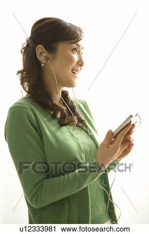 Stock Image - A Mature Adult Woman Listening to Music with a Portable Music Player, Side View. Fotosearch