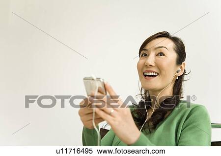 Stock Photography - A Mature Adult Woman Listening to Music with a Portable Music Player, Low Angle View, Copy Space. Fotosearch
