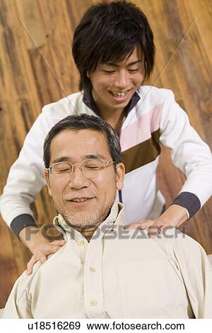 Stock Photo - A Son Massaging His Father's Shoulders, Low Angle View. Fotosearch