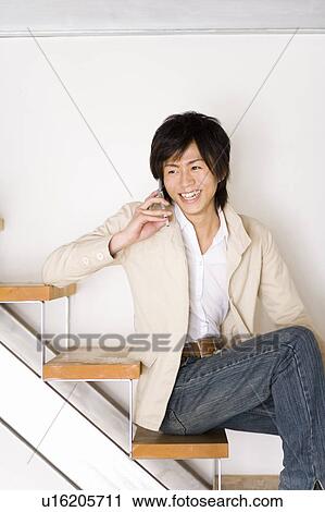 A Young Adult Man Sitting on Stairs and Talking on a Mobile Phone, Side View, Front View View Large Photo Image Stock Image - A Young Adult Man Sitting on Stairs and Talking on a Mobile Phone, Side View, Front View. Fotosearch