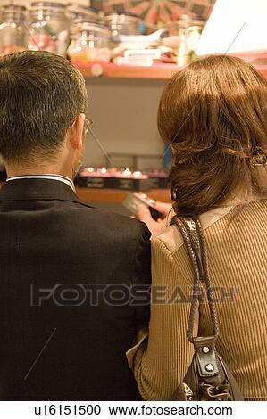 Stock Image - An Adult Couple Shopping Together, Rear View, Differential Focus. Fotosearch