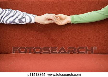 Stock Photography - Holding Each Other Hands on a Sofa, Close Up. Fotosearch