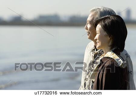 Stock Photograph - A Mature Couple Looking at the Sea, Head and Shoulder, Side View, Differential Focus. Fotosearch