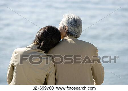 Stock Image - A Mature Couple Nestling Close to Each Other, Rear View, Waist Up. Fotosearch