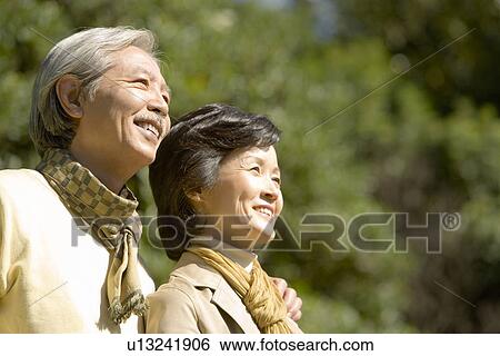 Stock Photograph - A Mature Couple Nestling Close to Each Other and Looking Away, Head and Shoulder, Low Angle View, Differential Focus. Fotosearch