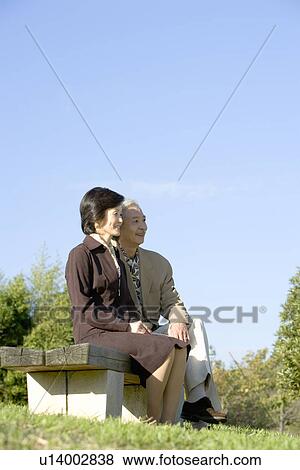 Stock Photo - A Mature Couple Sitting on a Bench, Full Length. Fotosearch