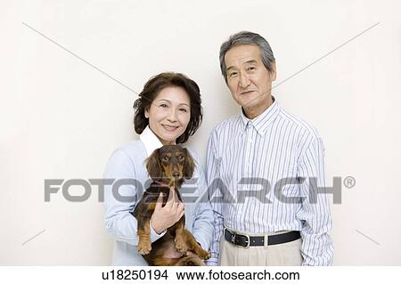 Picture - A Portrait of a Senior Adult Coupe Smiling at Camera with a Dog, Front View. Fotosearch