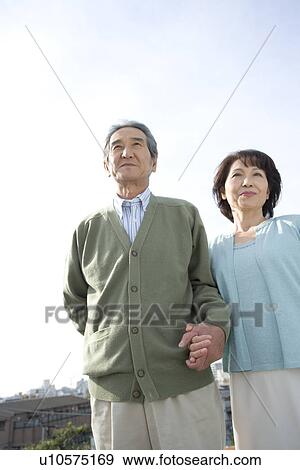 A Senior Adult Couple Holding Hands and Standing Together Under the Sky, Low Angle View View Large Photo Image Stock Photo - A Senior Adult Couple Holding Hands and Standing Together Under the Sky, Low Angle View. Fotosearch