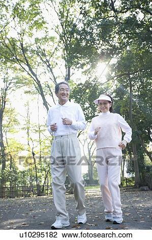 Stock Image - A Senior Adult Couple Jogging Together, Low Angle View. Fotosearch