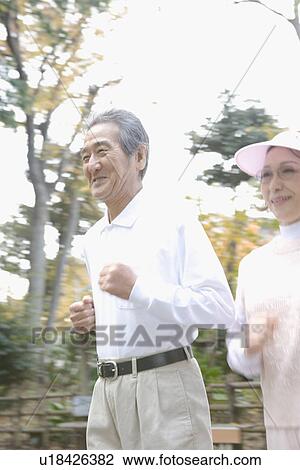 Stock Image - A Senior Adult Couple Jogging Together, Side View, Panning. Fotosearch