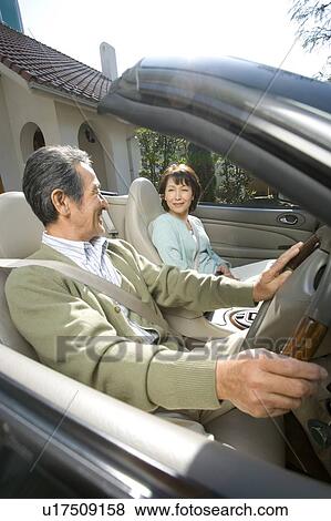 Stock Photo - A Senior Adult Couple on a Convertible Car, Side View. Fotosearch