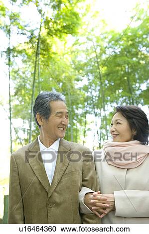 Stock Image - A Senior Adult Couple Walking Together in a Park, Low Angle View, Differential Focus. Fotosearch