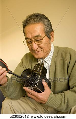 Stock Image - A Senior Adult Man Caring His Camera, Front View, Side View. Fotosearch