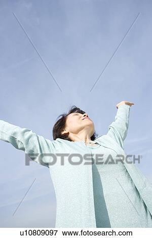 Stock Photo - A Senior Adult Woman Stretching Under the Sky, Low Angle View, Copy Space. Fotosearch