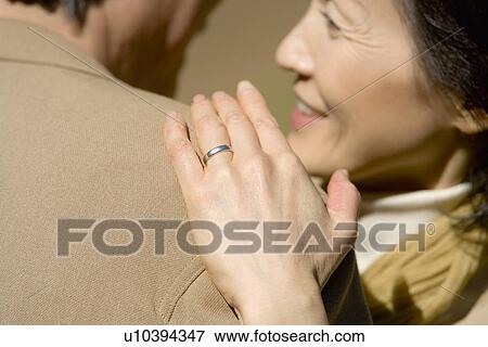 Stock Photo - Closed Up Image of a Ringed Hand on a Shoulder, Differential Focus. Fotosearch