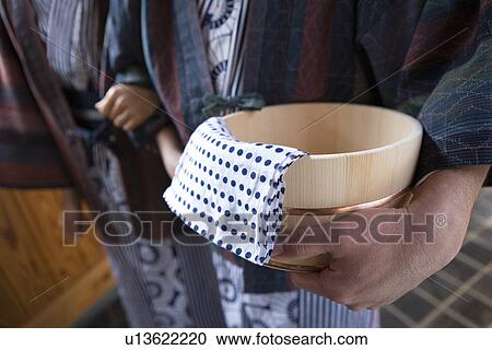 Stock Image - Close-up Image of a Wooden Pail Held By a Mature Adult, Side View, Differential Focus. Fotosearch