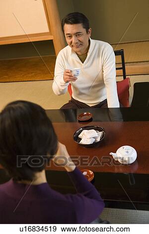 Stock Photo - Mature Adult Couple Drinking Tea in the Room of a Japanese-style Hotel, High Angle View, Front View, Rear View, Waist Up. Fotosearch