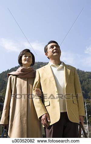Stock Image - Mature Adult Couple Holding Arms, Front View, Three Quarter Length, Low Angle View. Fotosearch
