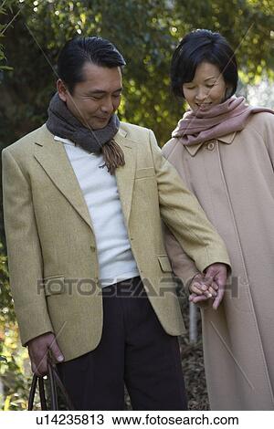Stock Image - Mature Adult Couple Holding Hands, Front View, Three Quarter Length. Fotosearch