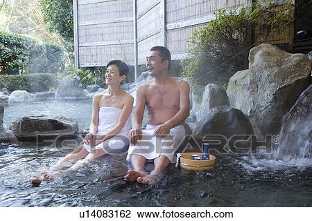 Stock Image - Mature Adult Couple Sitting at a Hot Spring, Front View, Full Length. Fotosearch