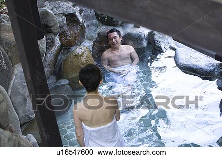 Stock Image - Mature Adult Couple Soaking in a Hot Spring Together, Front View, Rear View, High Angle View, Three Quarter Length. Fotosearch