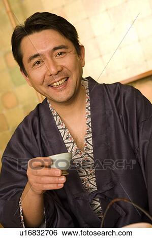 Stock Photograph - Mature Adult Man in Yukata Drinking, Looking at Camera, Front View, Waist Up. Fotosearch