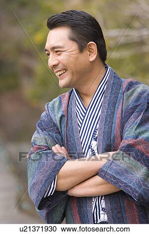 Stock Image - Mature Adult Man in Yukata Smiling and Crossing Arms, Front View, Waist Up, Differential Focus. Fotosearch